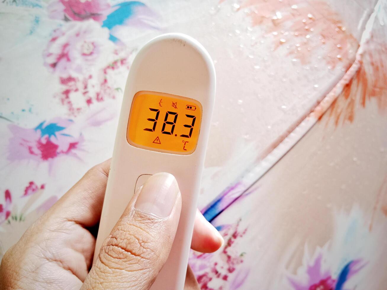 Fever Warning. Non-contact digital medical infrared forehead thermometer Reading fever temperature during the rainy season photo