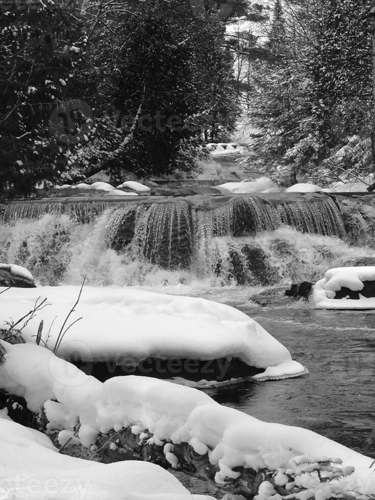 Waterfall in a Snowy Landscape with Tree Branches and Fluvial Features photo