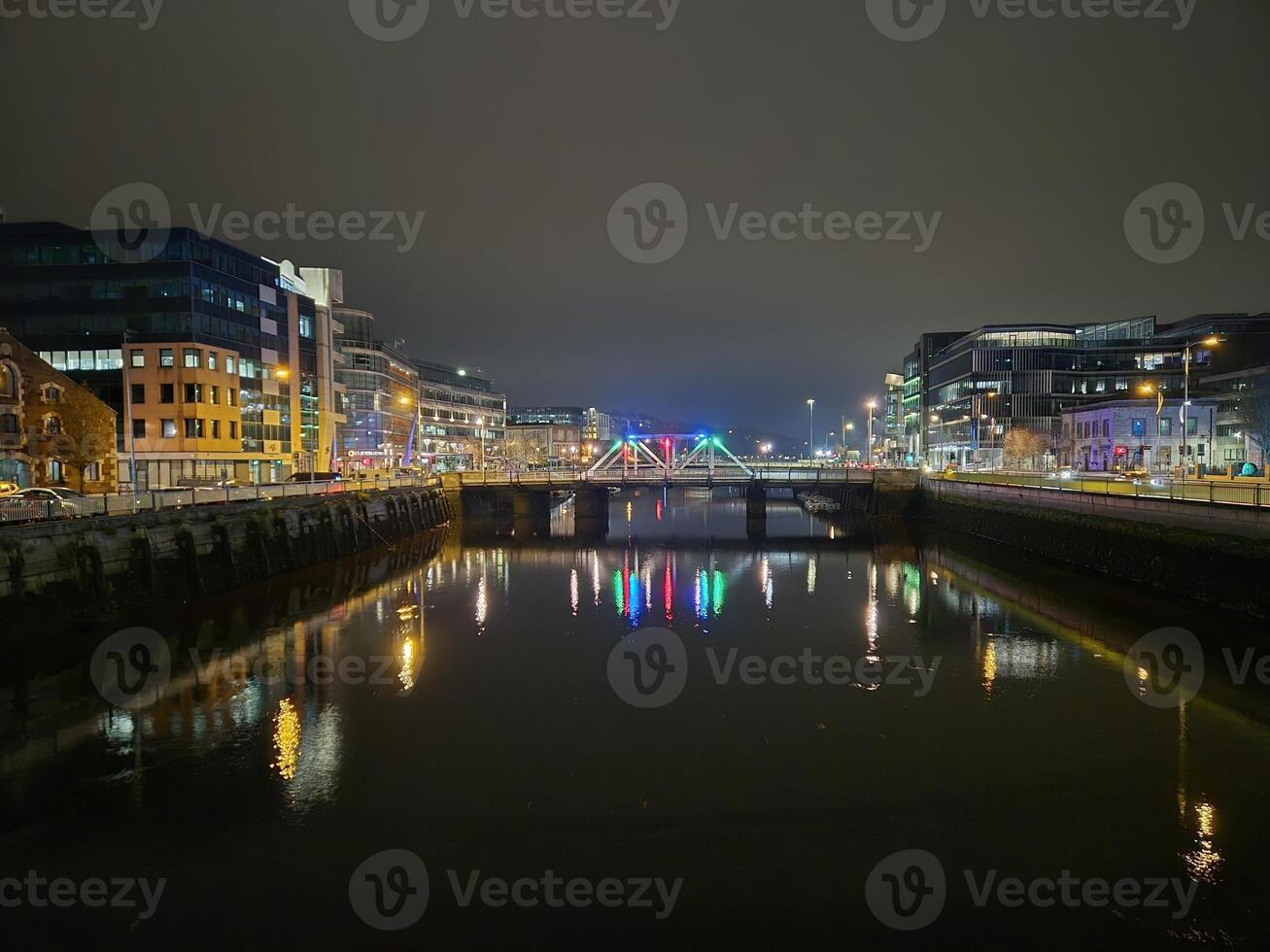 Cityscape at Dusk with Tower Blocks and Bridge Over Lake photo