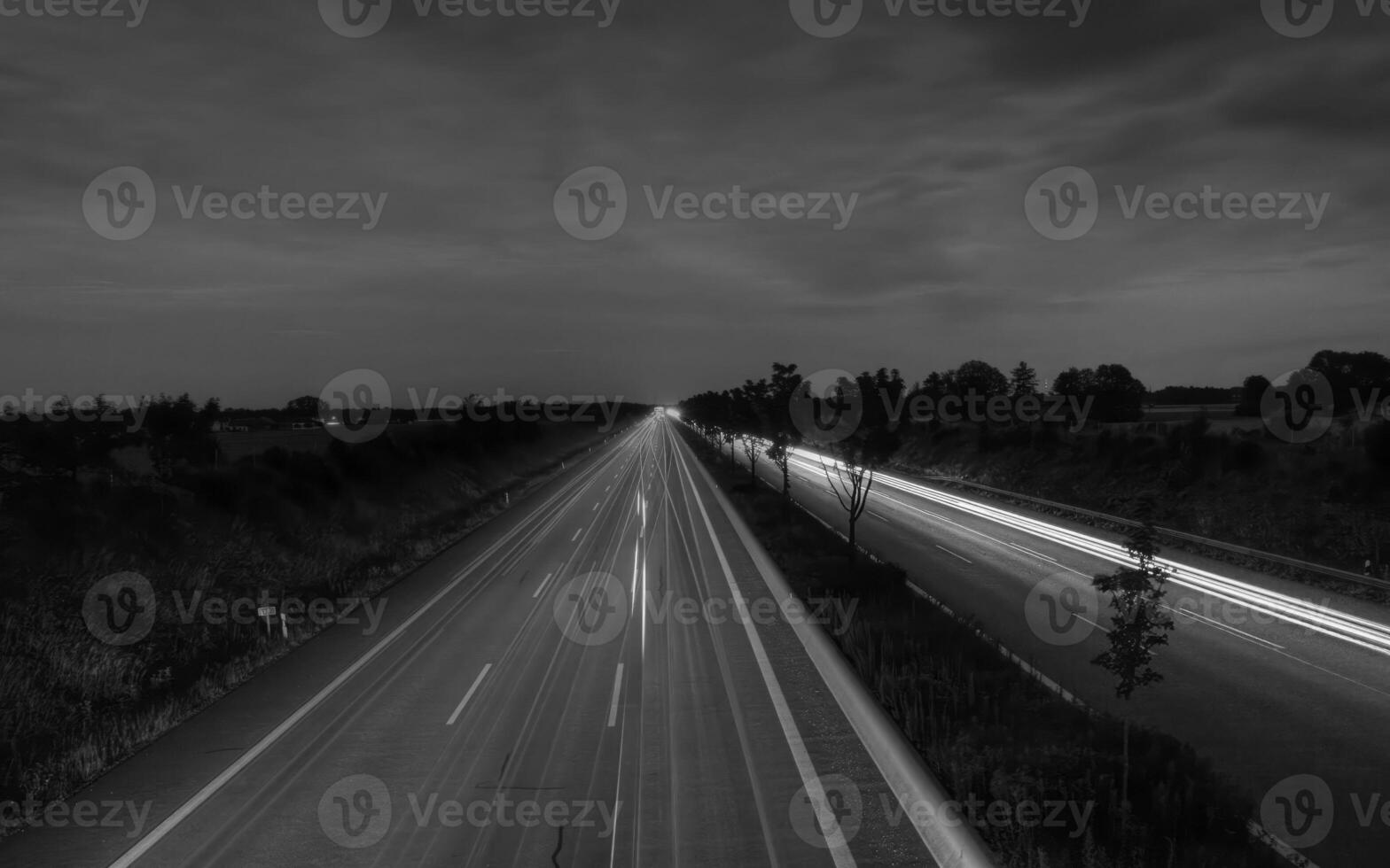 Tranquil Roadway Beneath a Cloudy Sky with Lush Greenery photo