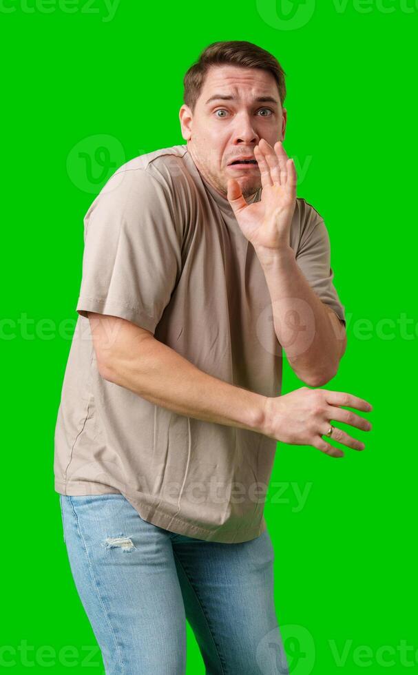 Man expressing fear while standing against a bright green background photo
