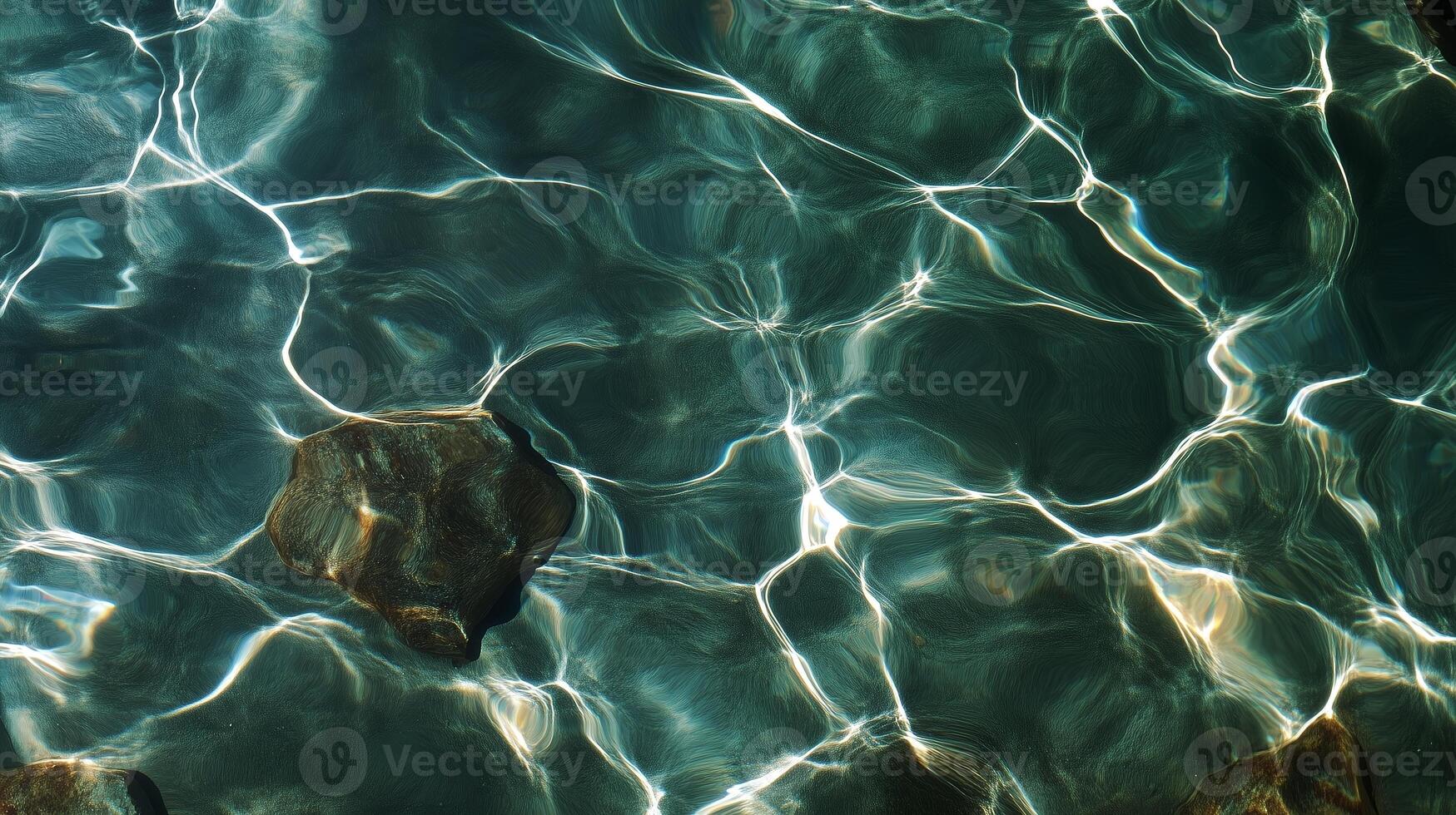 Clear water ripples reflect sunlight, revealing a stone beneath the surface in a tranquil setting photo
