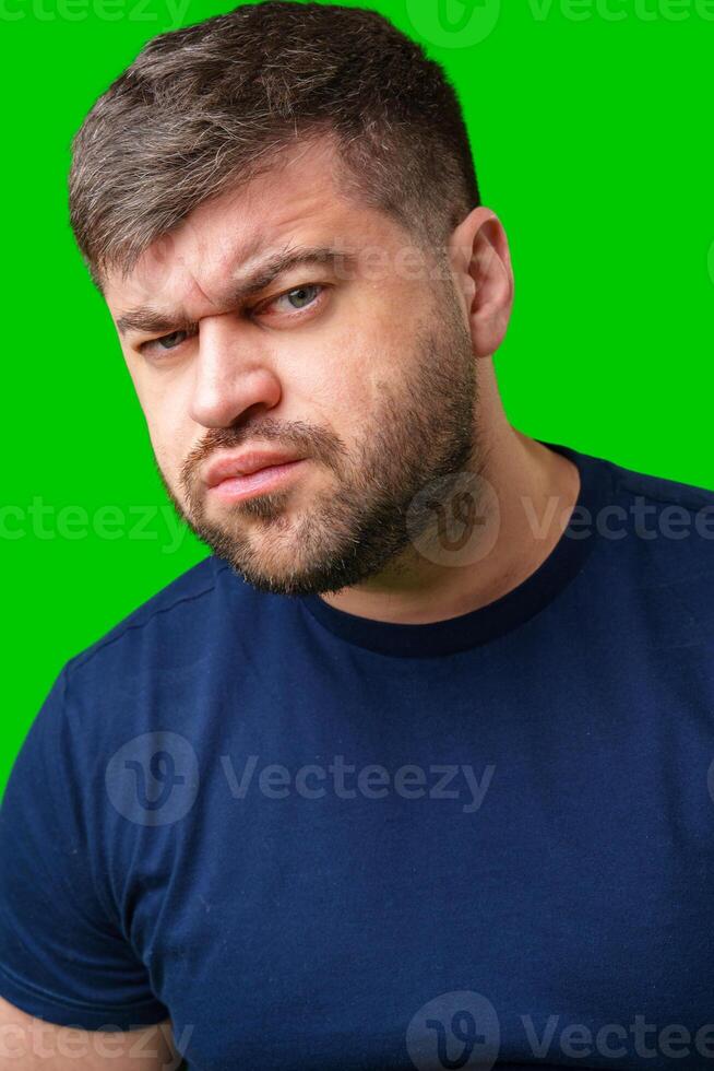 Man expressing confusion with crossed arms in front of a bright green background photo