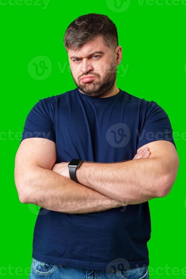Man expressing confusion with crossed arms in front of a bright green background photo