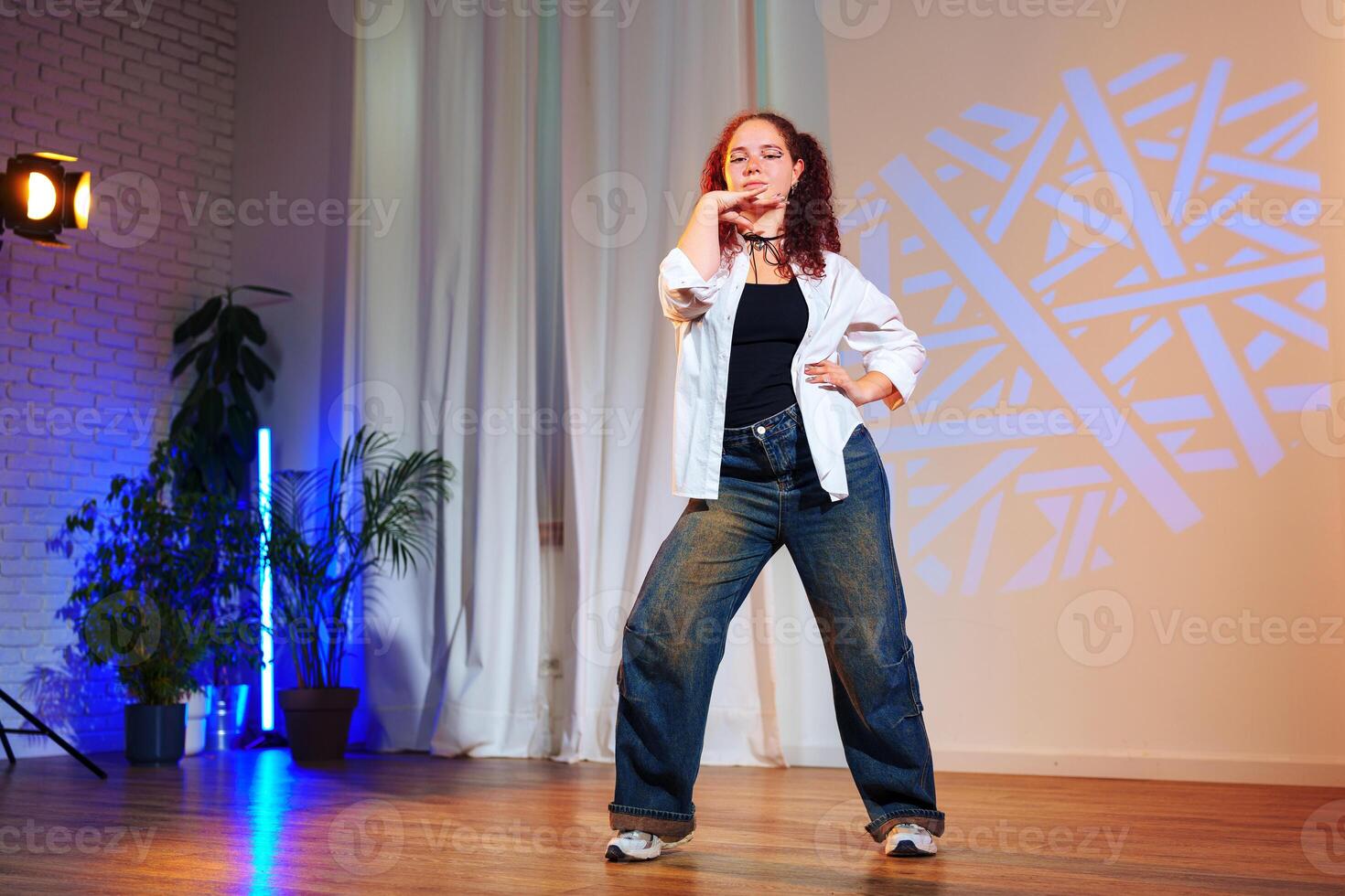 A woman poses on a dance floor in front of a light projection photo