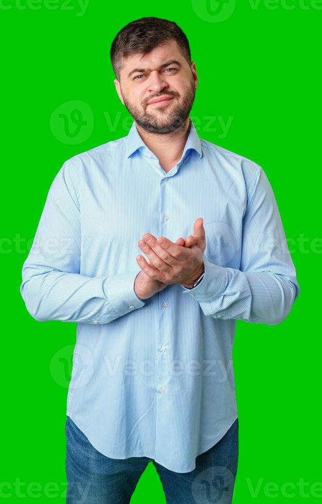 A man wearing a blue-striped shirt stands against a green background photo