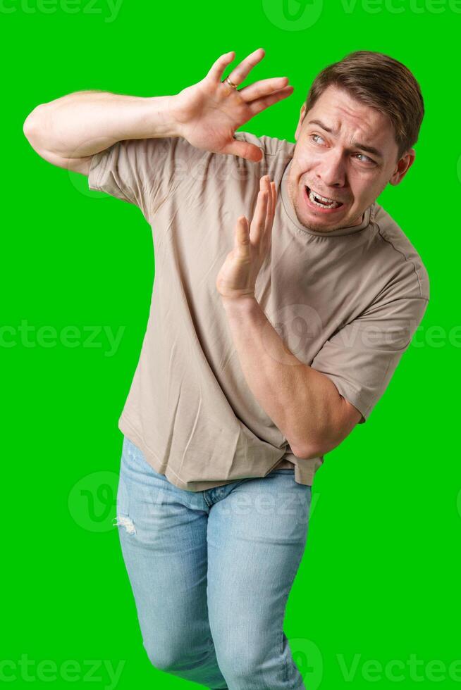 Man expressing fear while standing against a bright green background photo