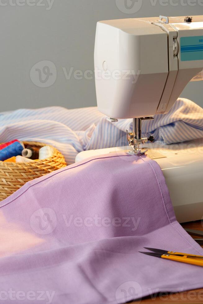 Sewing machine in use on a wooden table, stitching a light fabric in a well-lit indoor workspace photo