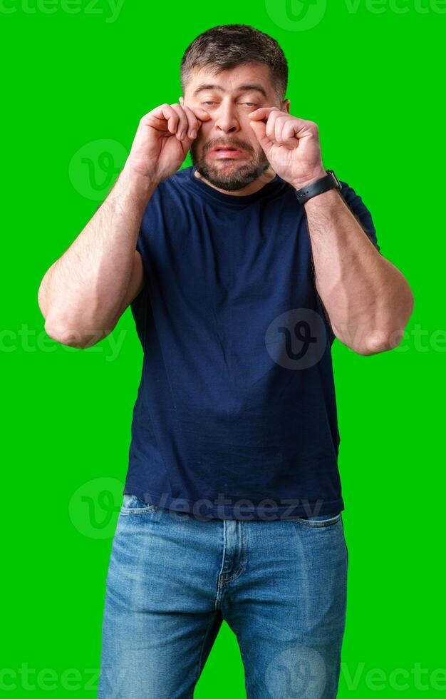Man expressing frustration with tired eyes while standing in front of a bright green background photo