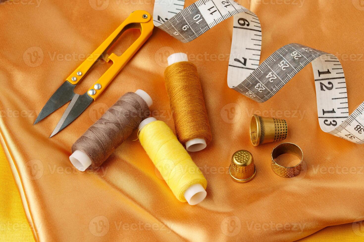 Sewing tools and materials arranged on a luxurious golden fabric background in a creative crafting workspace photo