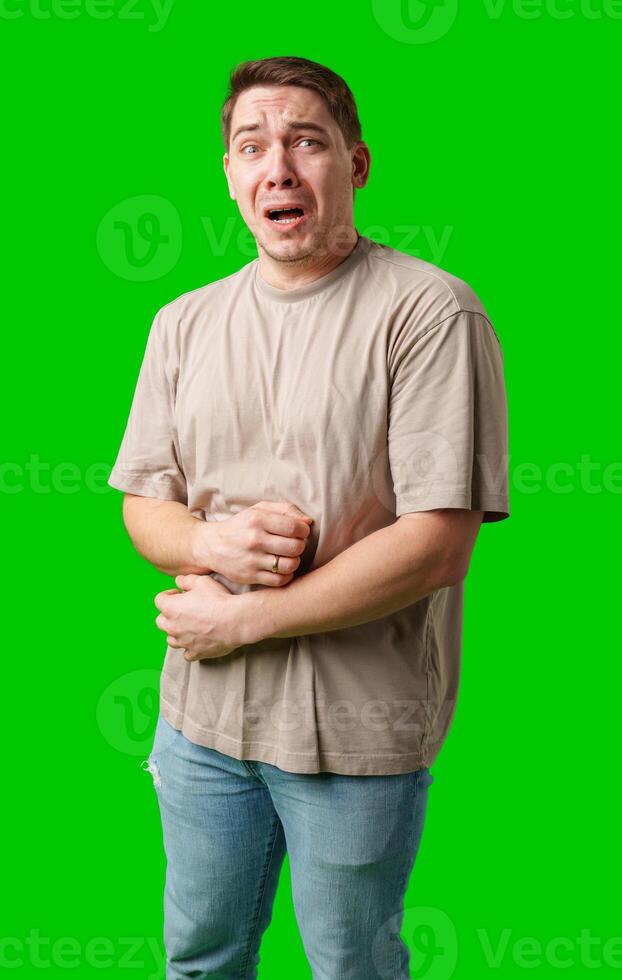 Man expressing fear while standing against a bright green background photo