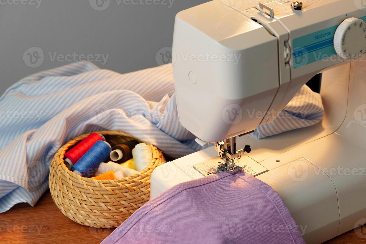 Sewing machine in use on a wooden table, stitching a light fabric in a well-lit indoor workspace photo