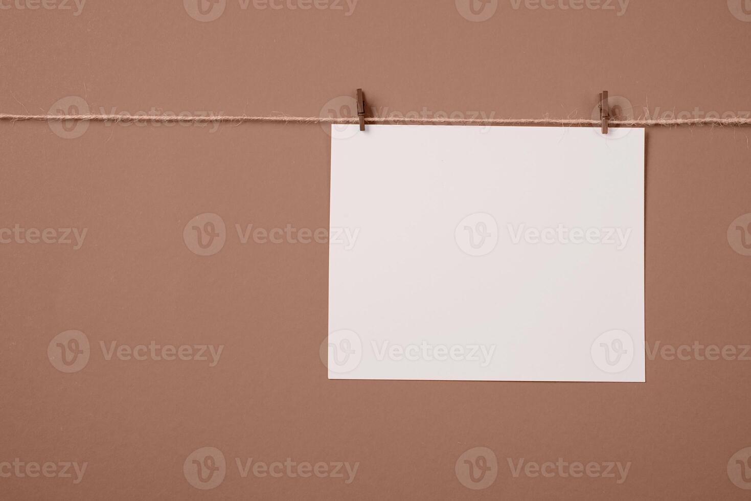 Mocha Mousse - color of the year 2025. Note paper card hanging with wooden clip or clothespin on rope string peg isolated photo