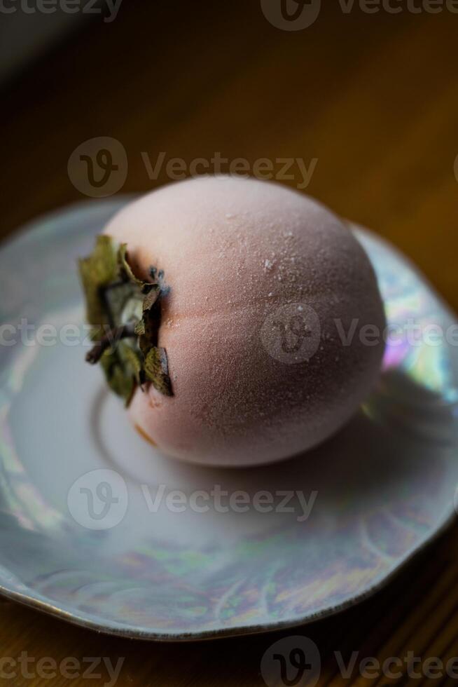 Frozen persimmon on a saucer. Persimmon covered with frost photo