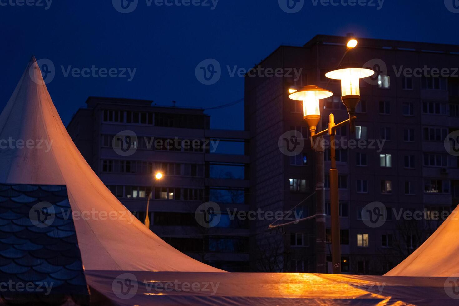 Soviet panel houses in the distance in the evening. A burning street lamp photo