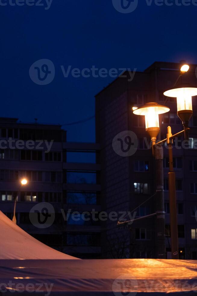 Soviet panel houses in the distance in the evening. A burning street lamp photo