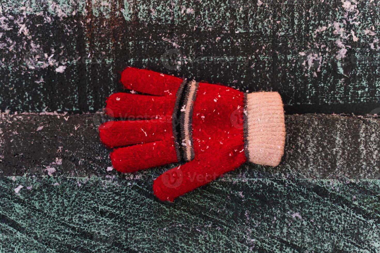 A red glove in the snow, on a wooden background. Christmas background photo