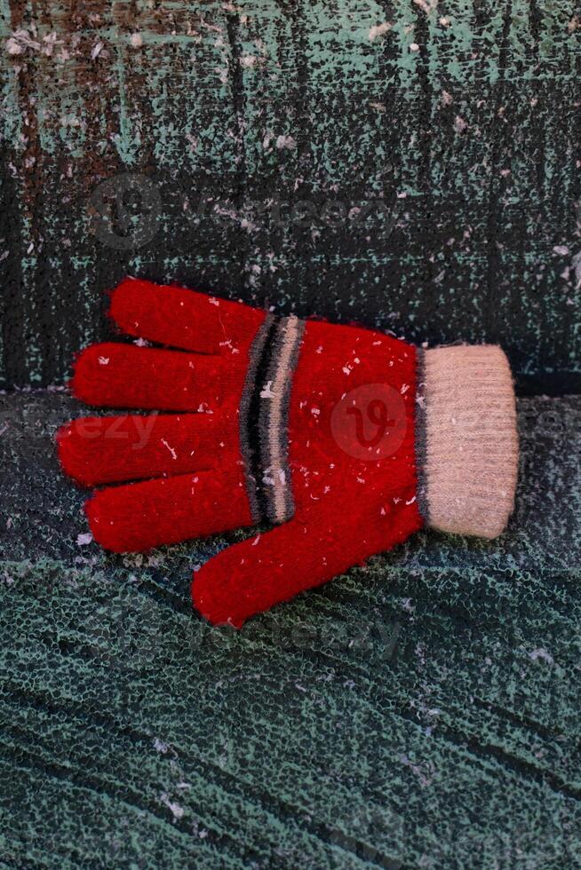 A red glove in the snow, on a wooden background. Christmas background photo