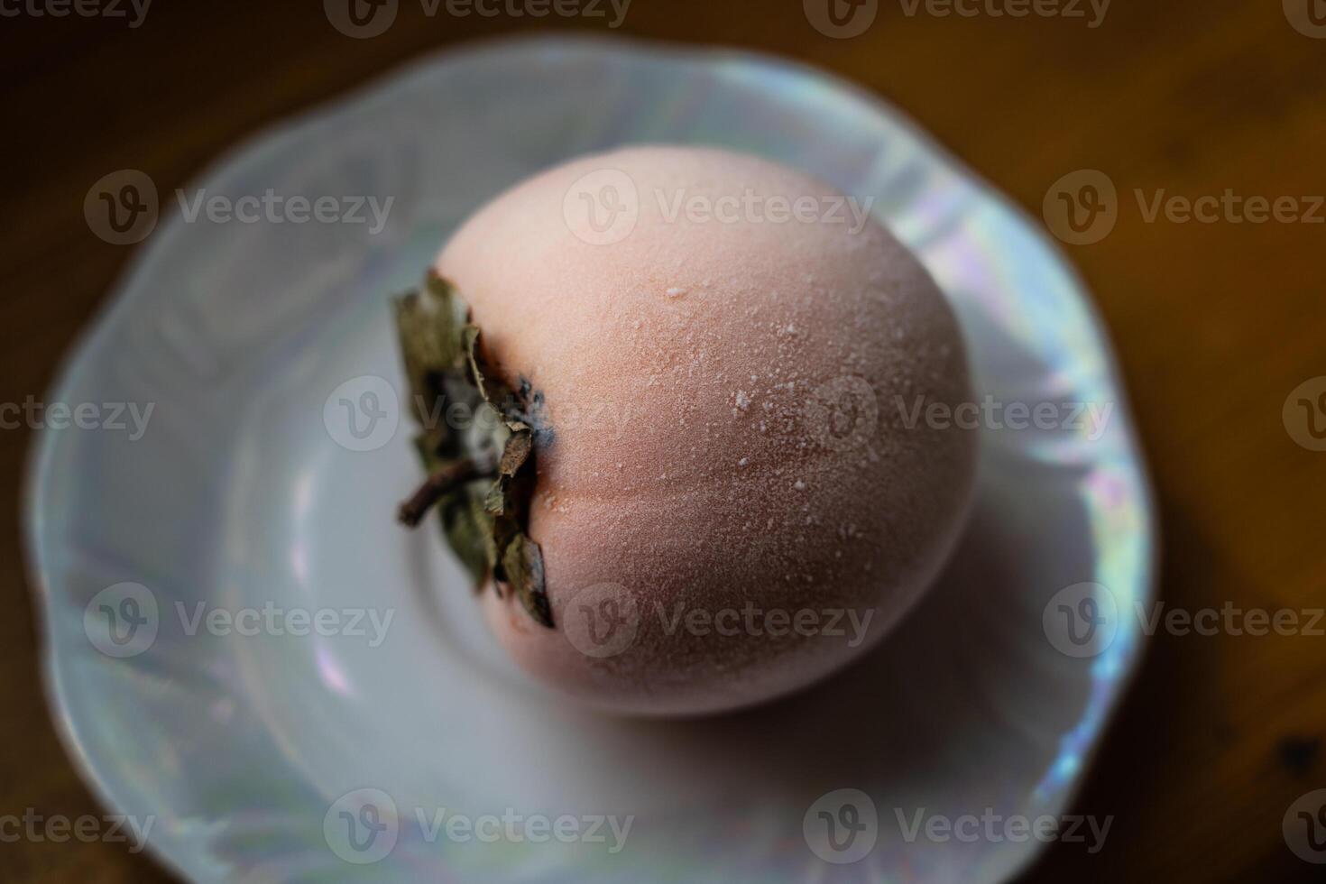 Frozen persimmon on a saucer. Persimmon covered with frost photo