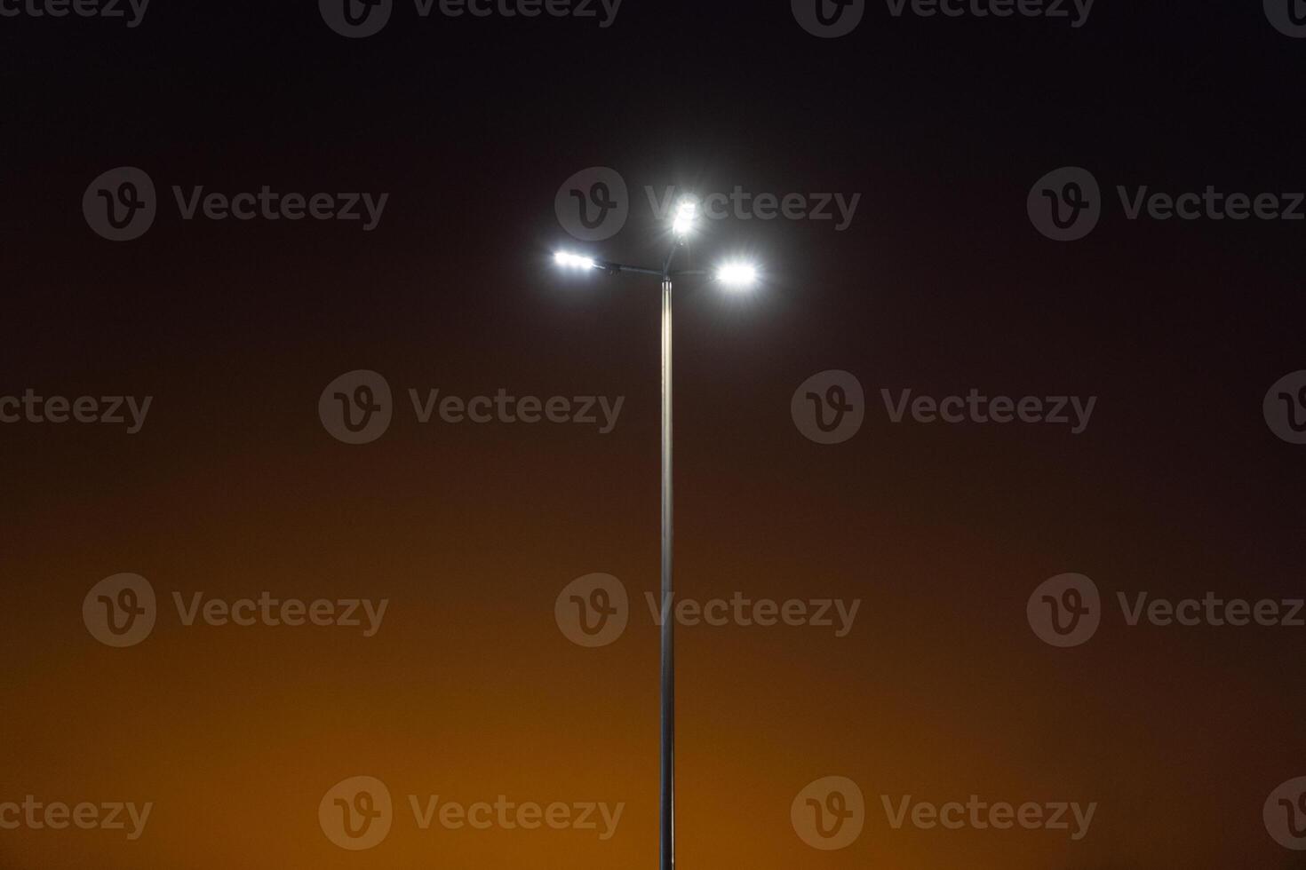 A street lamp in the evening against an orange sky background. Minimalism photo
