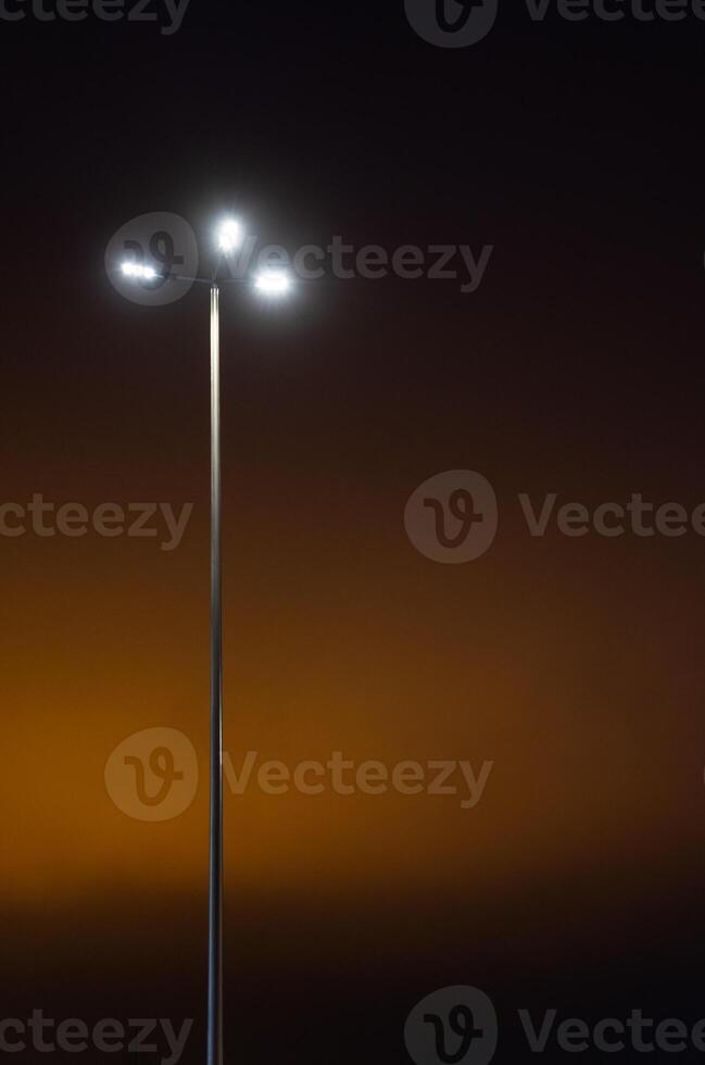 A street lamp in the evening against an orange sky background. Minimalism photo
