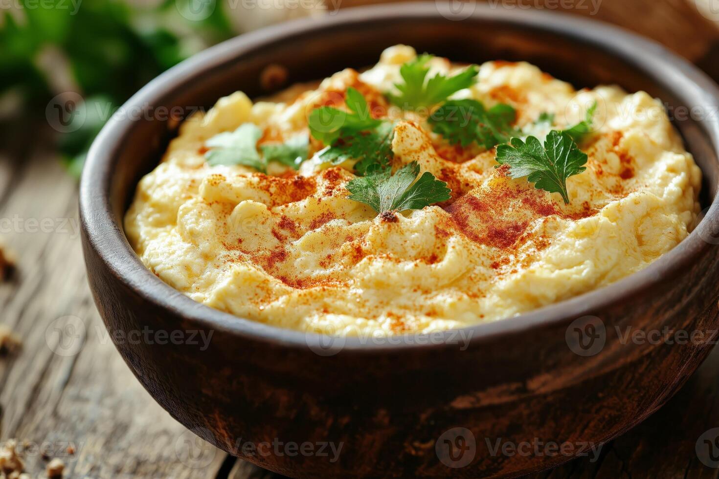 Creamy polenta or mashed potatoes sprinkled with paprika and parsley in rustic wooden bowl photo