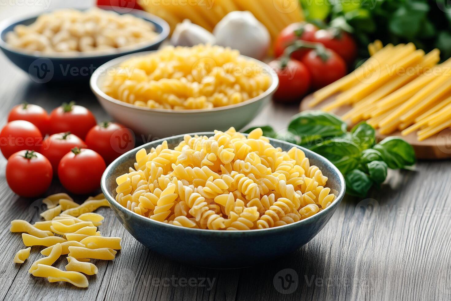 Bowls of uncooked pasta with tomatoes, garlic, and basil on rustic table photo