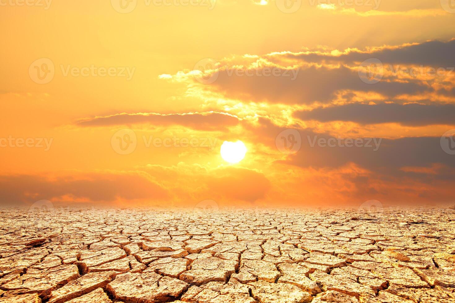 A dramatic landscape of parched earth with deep cracks, set against a fiery sunset, evokes a sense of vulnerability, change photo