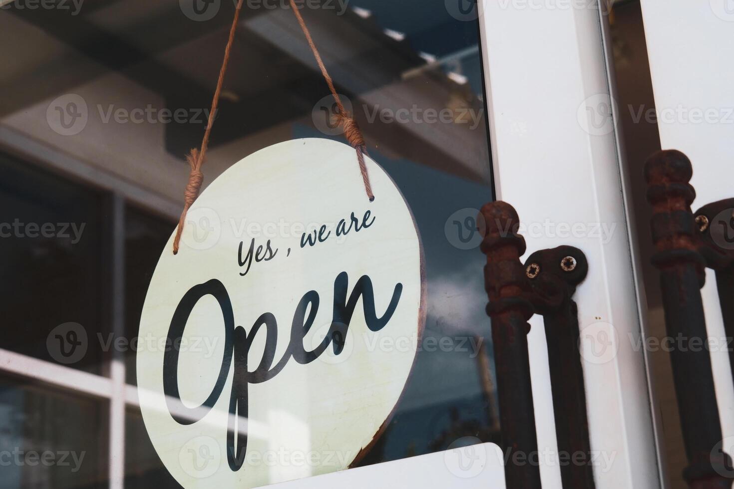 Rustic Open Sign Hanging on Glass Door of a Small Business Shop Inviting Customers Inside on a Sunny Day photo