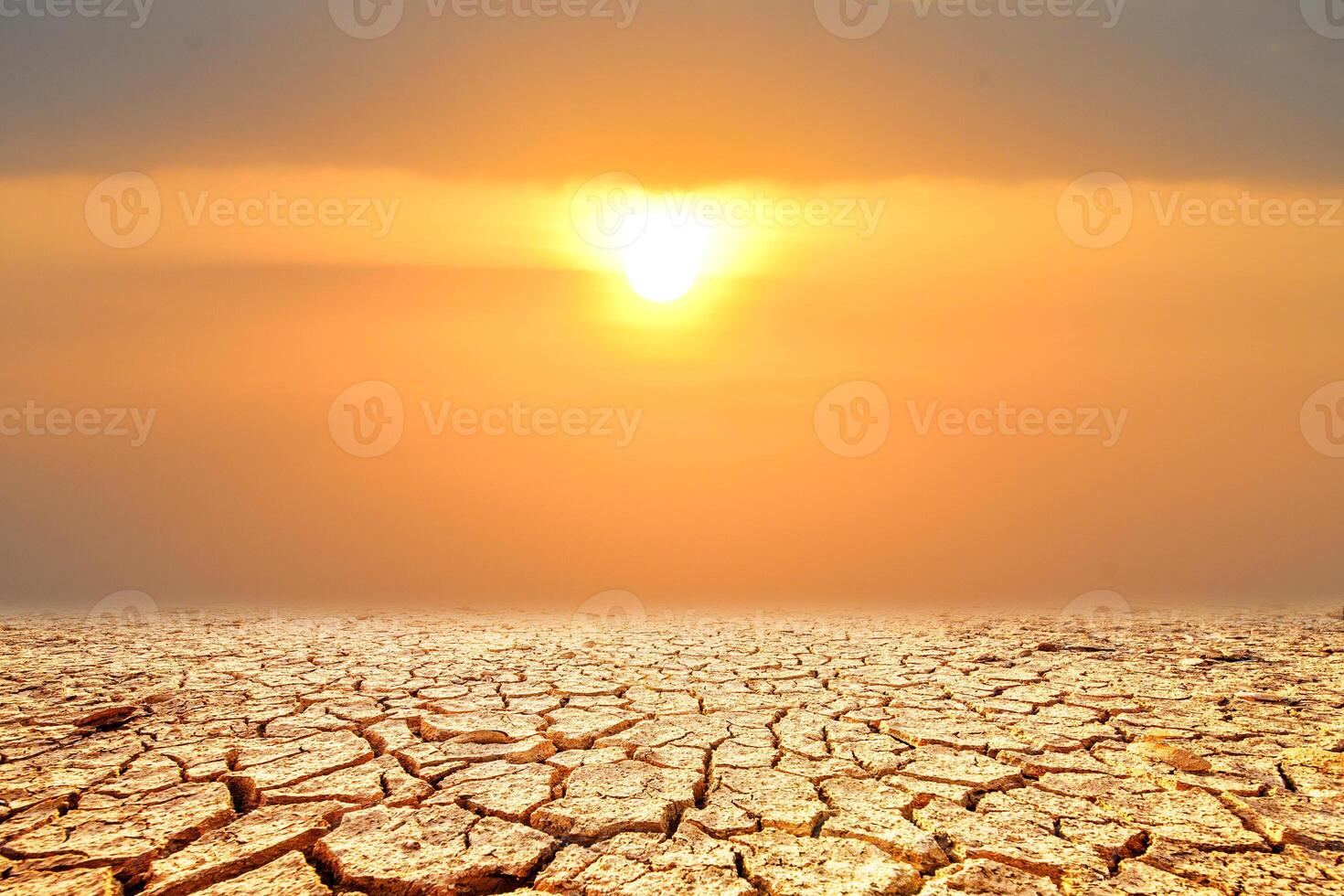 A dramatic landscape of parched earth with deep cracks, set against a fiery sunset, evokes a sense of vulnerability, change photo