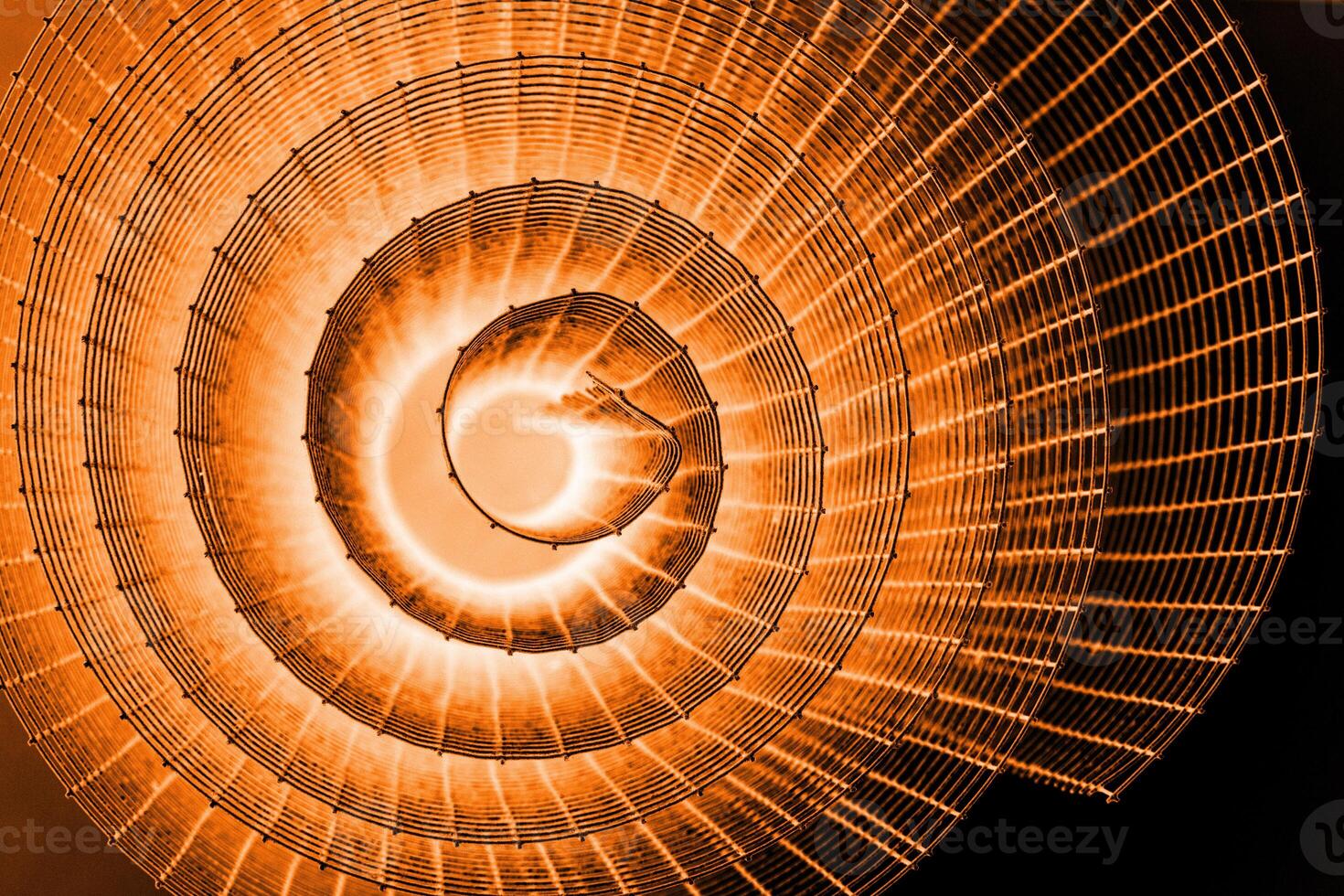 Abstract spiral with glowing red and orange tones and wire texture against a black background, symbolizing energy, motion, industrial and futuristic design concepts. Copy space photo