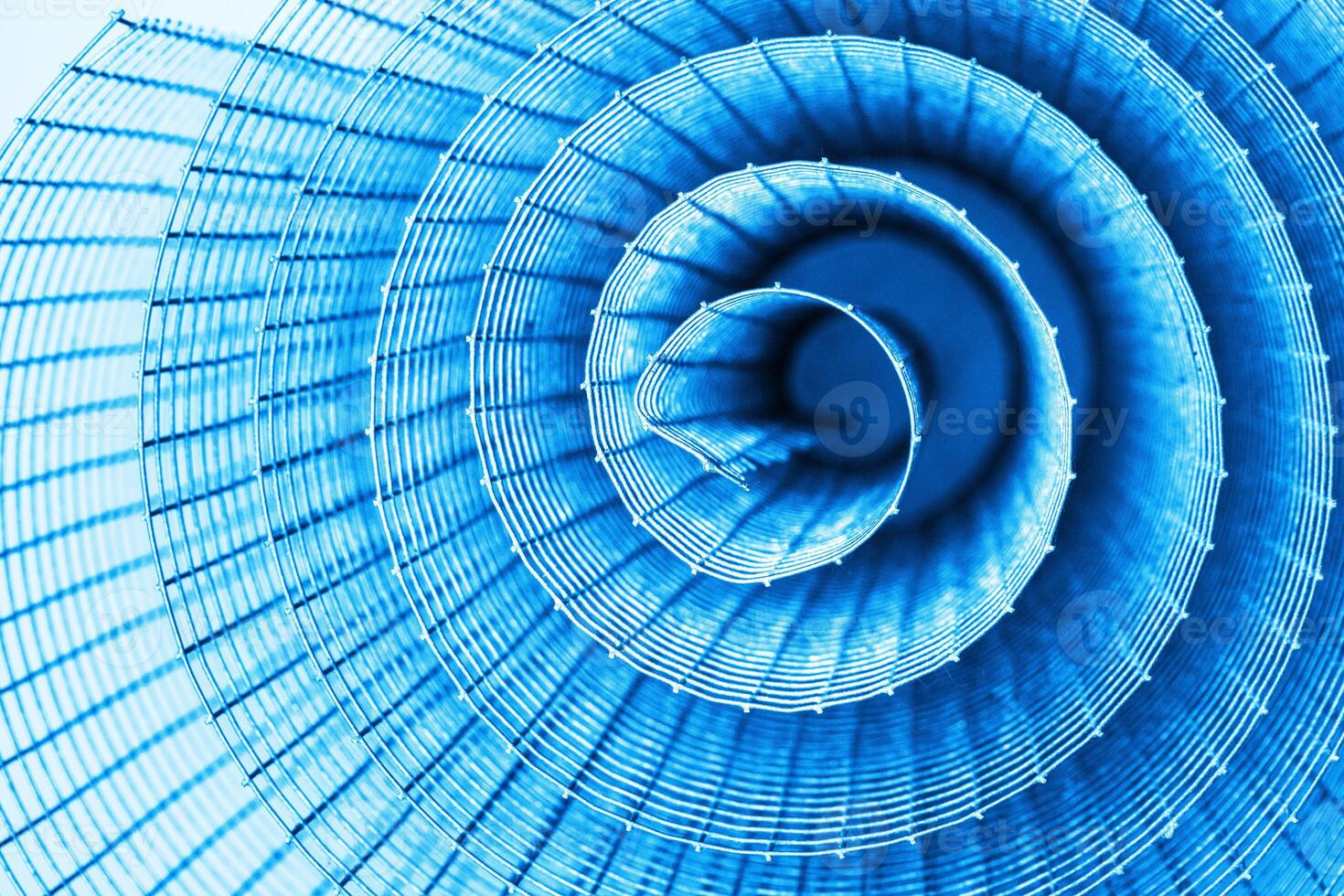 Abstract spiral metal coiled wire mesh with blue grid pattern, geometric symmetry, minimalist design for industrial construction, diy, architectural concepts. Isolated on white background. Copy space photo