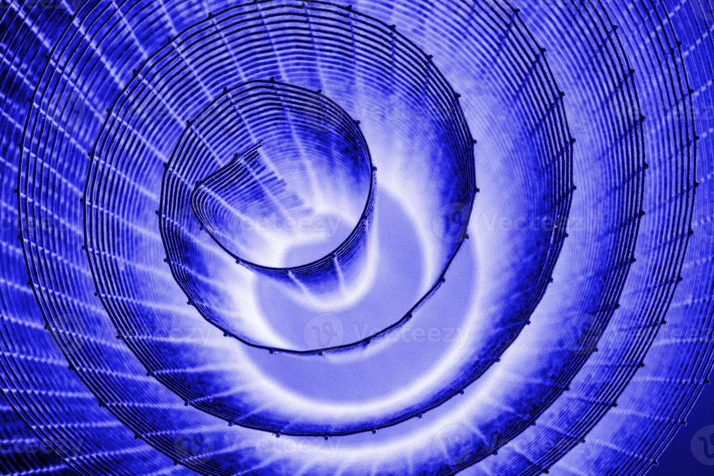 Abstract spiral with glowing blue, lilac, violet, purple tones and wire texture against a black background, symbolizing energy, motion, industrial and futuristic design concepts. Copy space photo