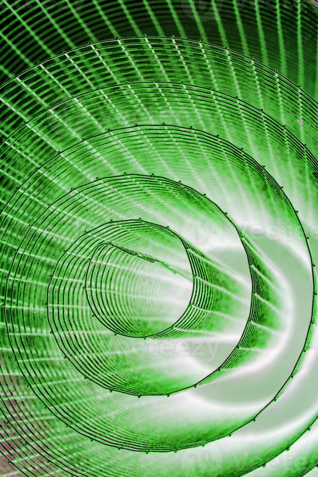 Abstract spiral with glowing green wire texture against a black background, symbolizing color contrast, energy, motion, industrial and futuristic design concepts. Copy space photo