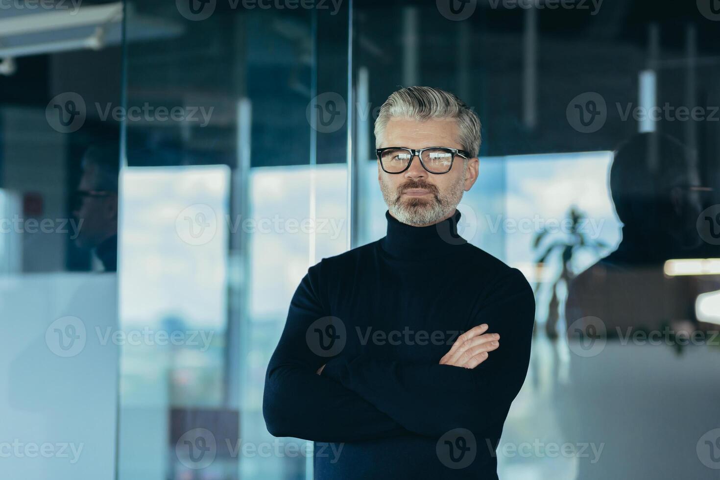 Portrait of serious and focused businessman with crossed arms, man working in office wearing glasses looking at camera, successful thoughtful investor photo
