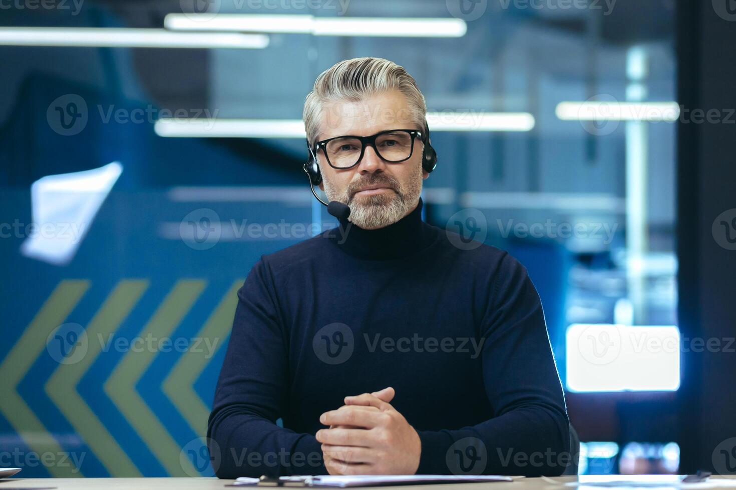 call, serious and mature businessman looking thoughtfully at camera, gray-haired man using headset for remote communication and online meeting. photo
