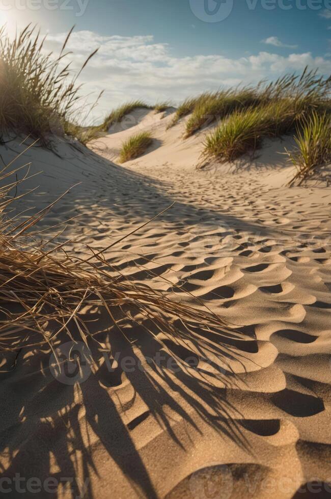 A serene landscape of sand dunes with grass under a bright sky. photo
