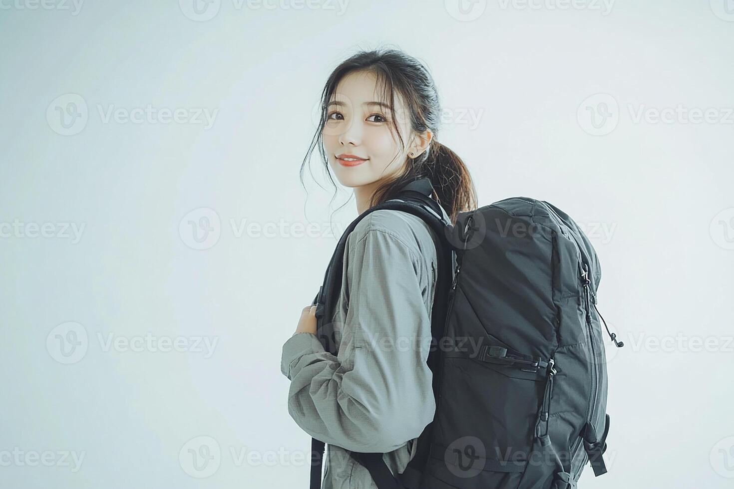 A woman with a backpack standing in front of a white background photo