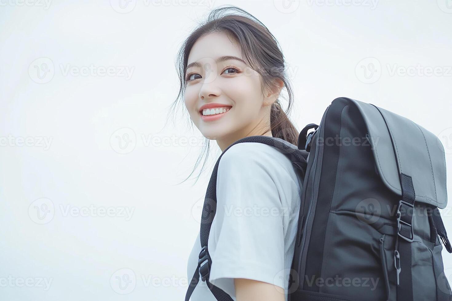 A woman with a backpack smiles while standing photo