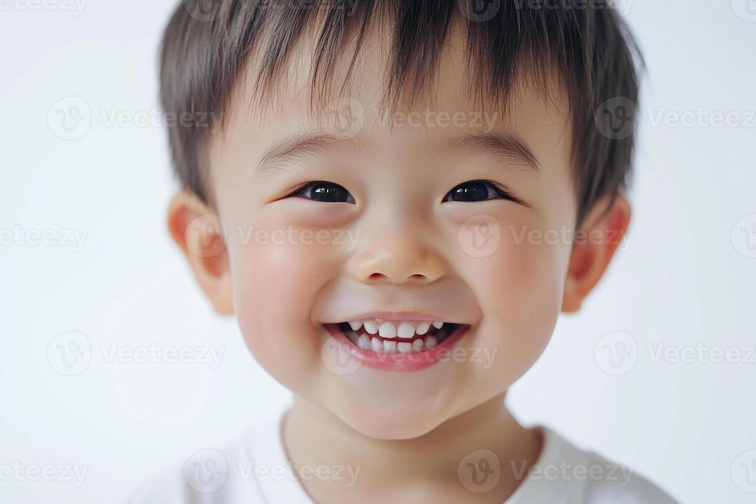 A young boy smiles while standing in front of a white background photo