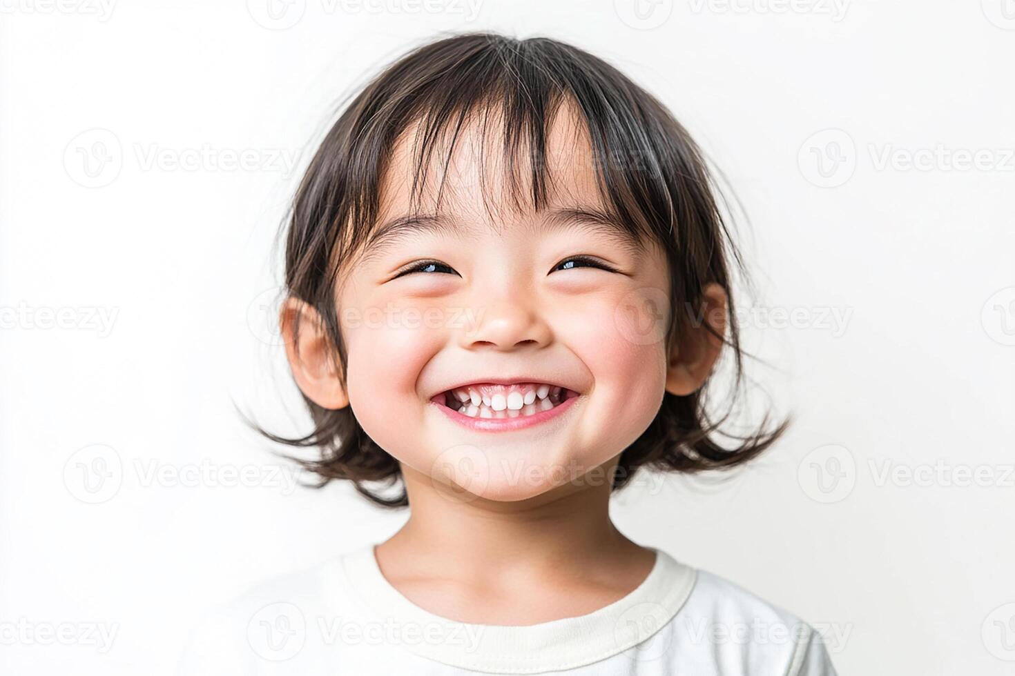 A little girl smiles while standing in front of a white background photo
