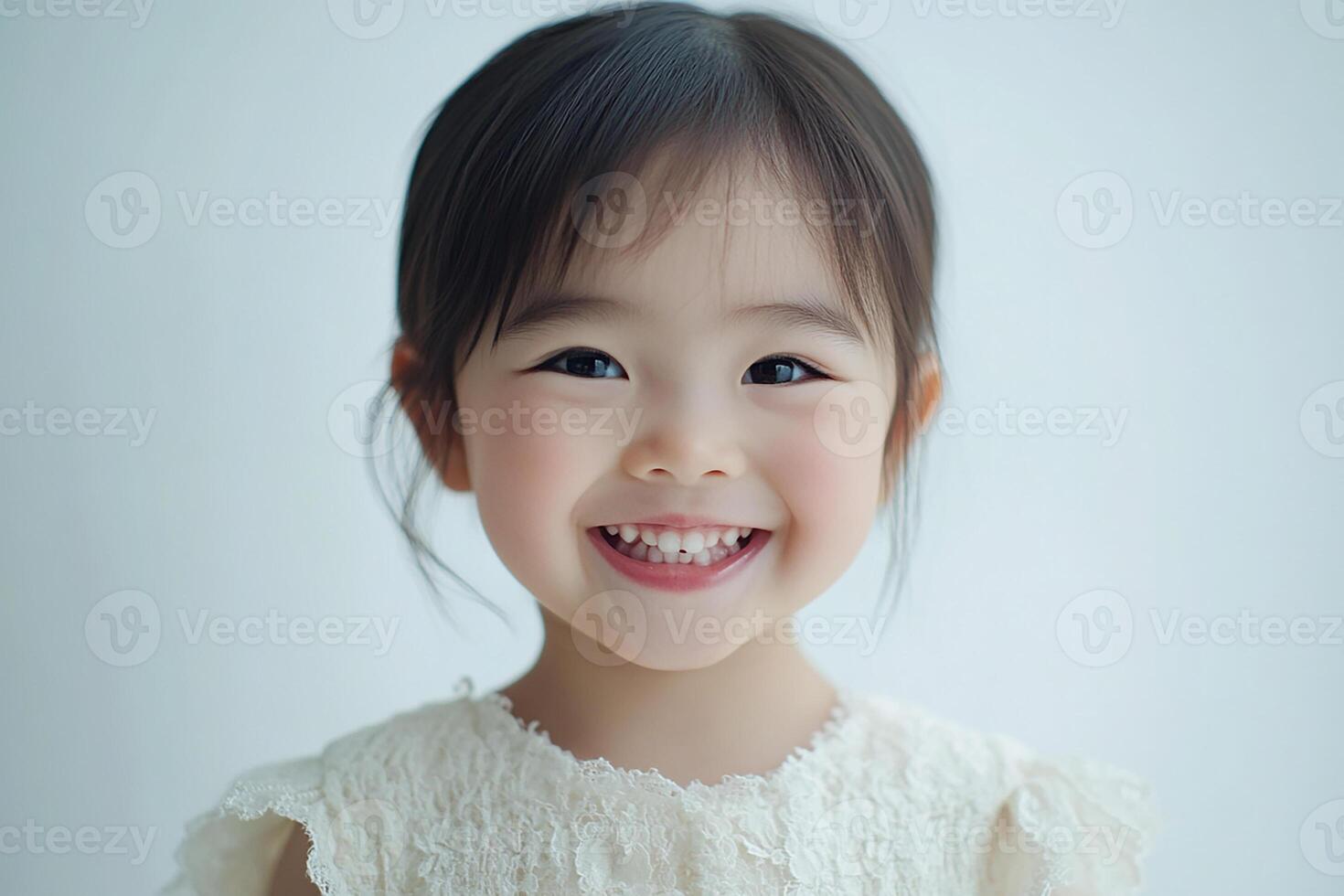 A little girl smiles while wearing a white dress photo