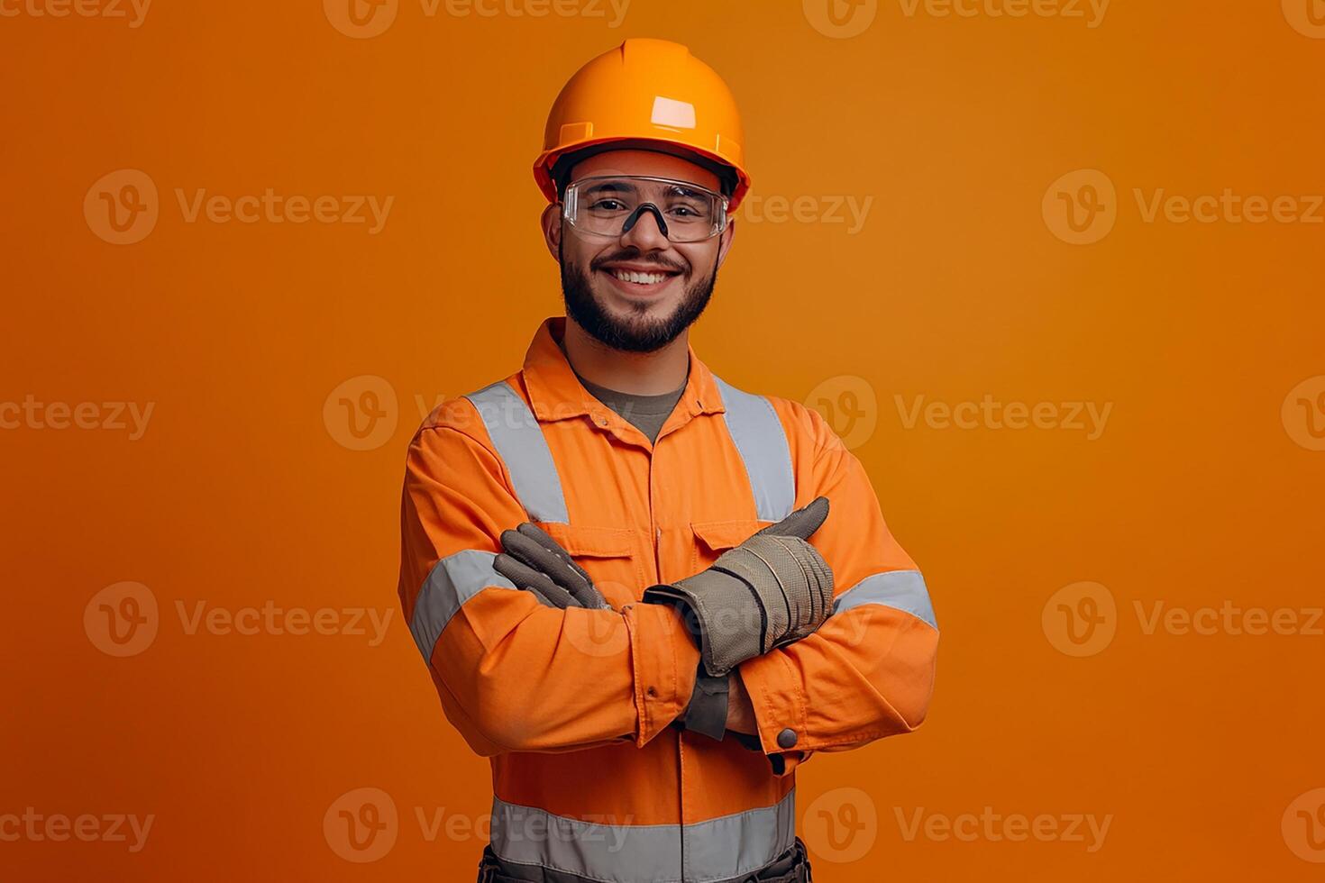Portrait of a young man in an orange safety suit standing with his arms crossed on an orange photo