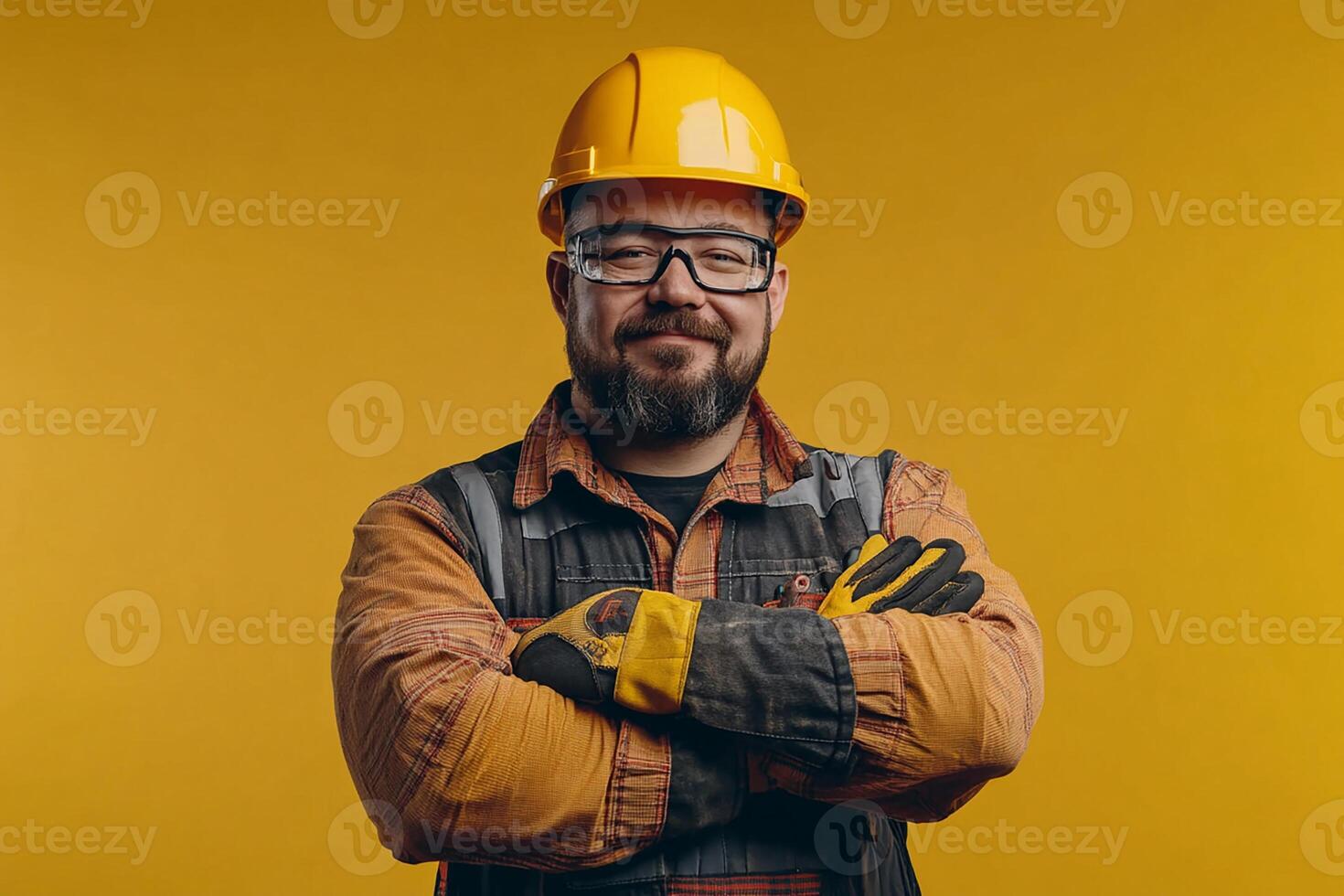 Portrait of a smiling man in hard hat and glasses standing in front of yellow background photo