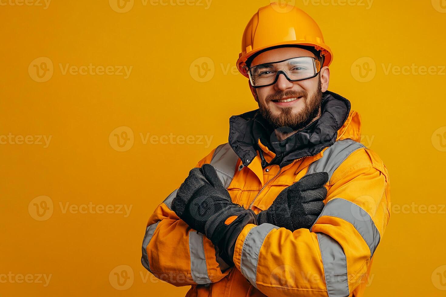 Portrait of a smiling man in a hard hat and safety glasses on a yellow background photo