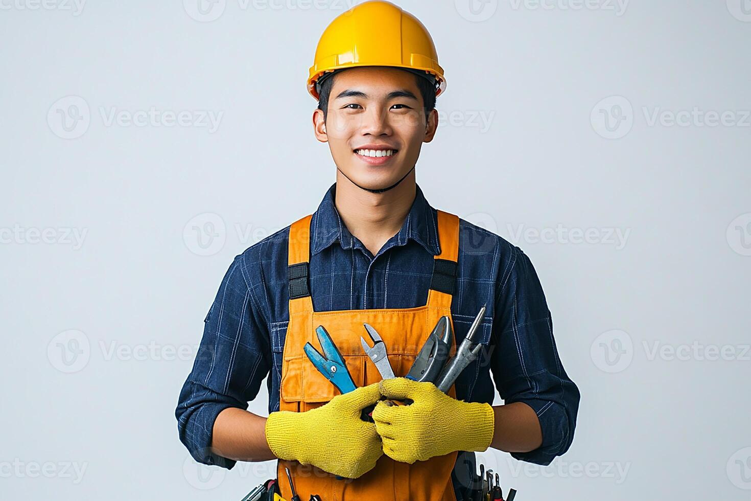 A young man in an orange hard hat holding a pair of pliers photo