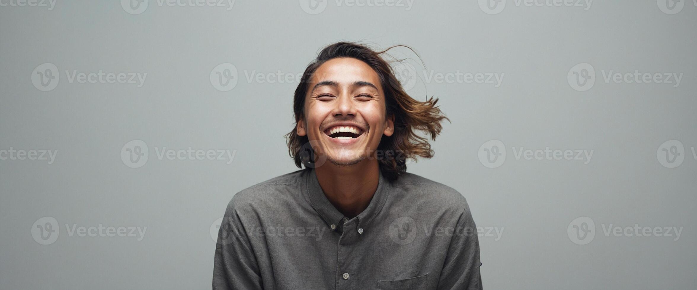 A man is smiling while standing in front of a gray background photo