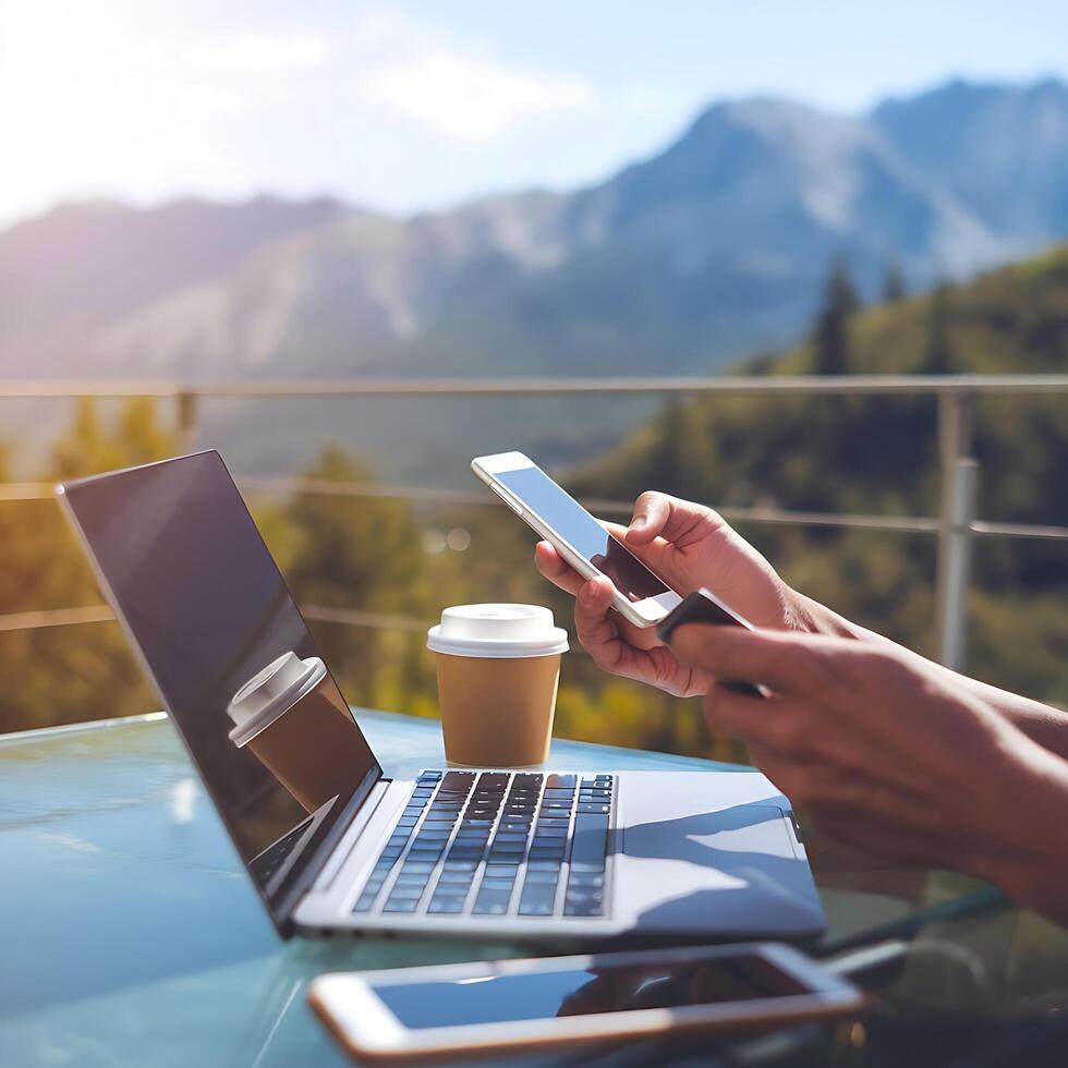 A man using his laptop and mobile phone in front of a mountain view photo