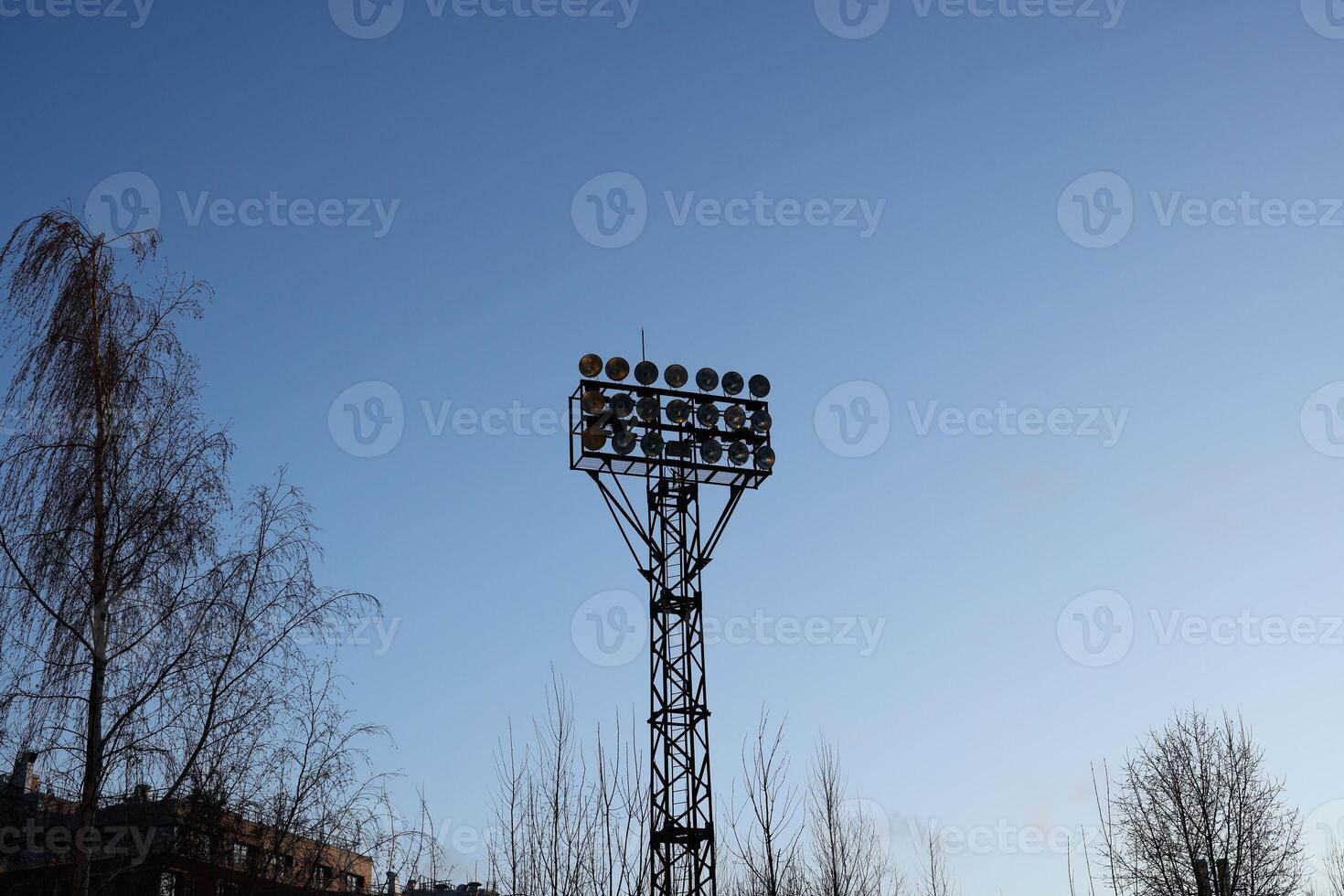 A tall sports field floodlight tower standing majestically against the clear blue sky above photo