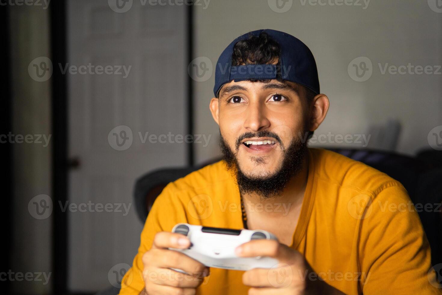Young man playing videogames with a wireless controller at home photo